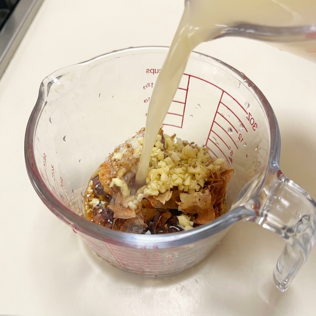 調味料の入ったカップに、白濁した熱い豚骨スープを注いでいる様子。