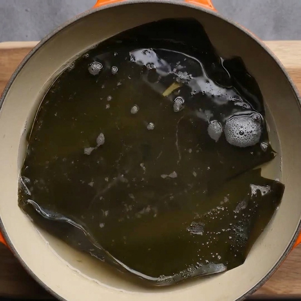 沸騰した鍋で大きなだし昆布を煮出している様子。