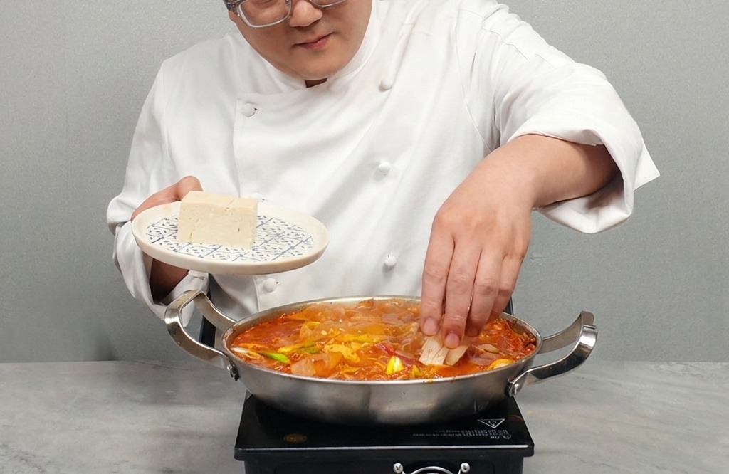 熱々のスープの上に、厚切りにした木綿豆腐を並べている様子。
