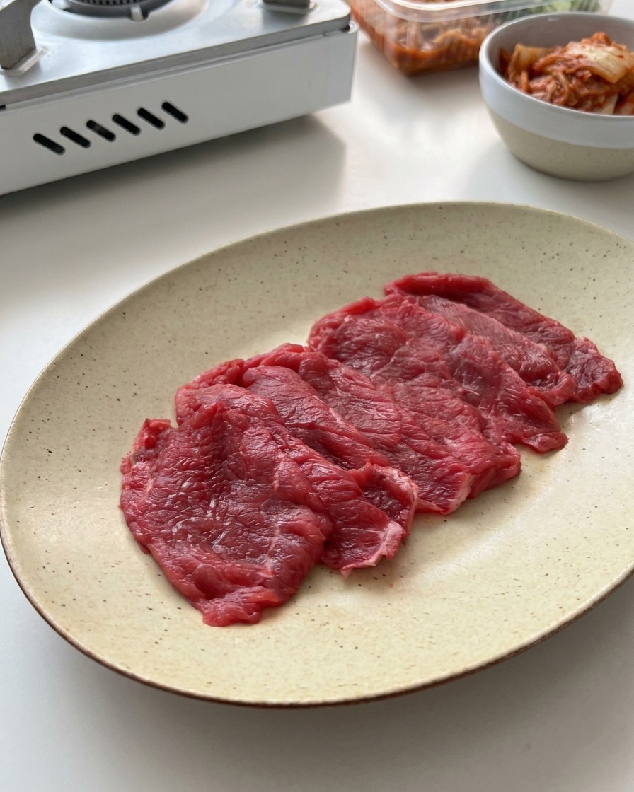 斑点模様のある白いセラミック皿に並べられた牛肉の薄切り。