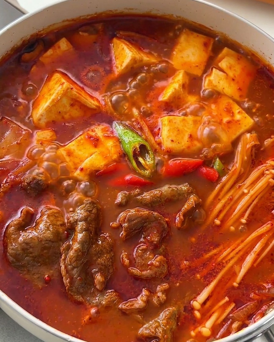 斜め切りにした赤と緑の唐辛子が散らされた、出来立ての牛肉入りキムチチゲ。