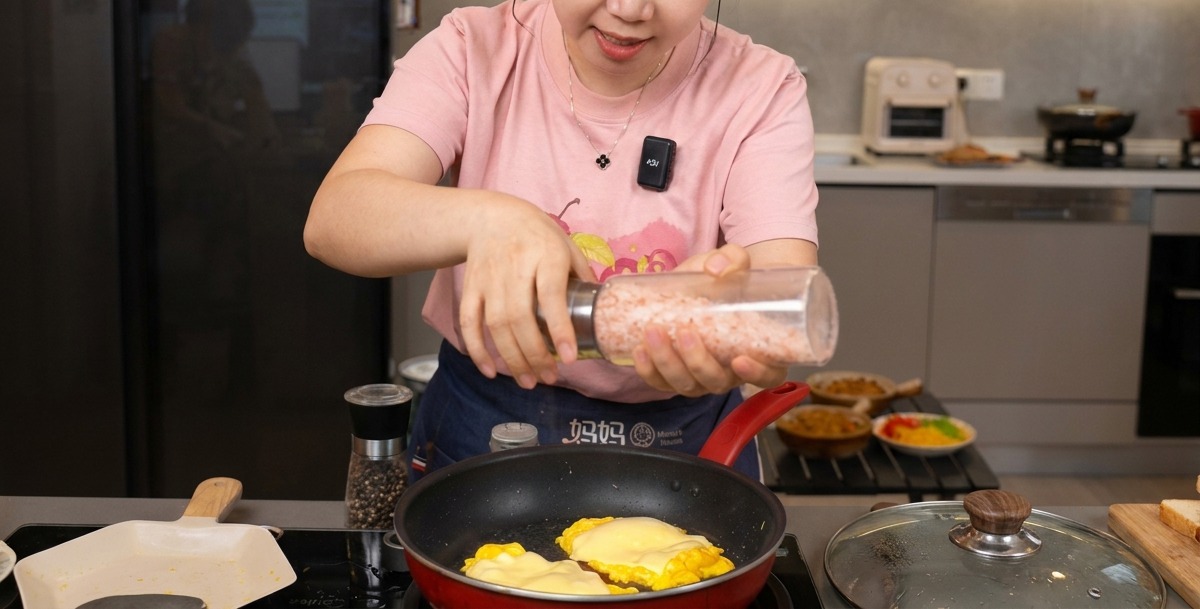 フライパンの中のチーズ卵に海塩と黒こしょうを振っている様子