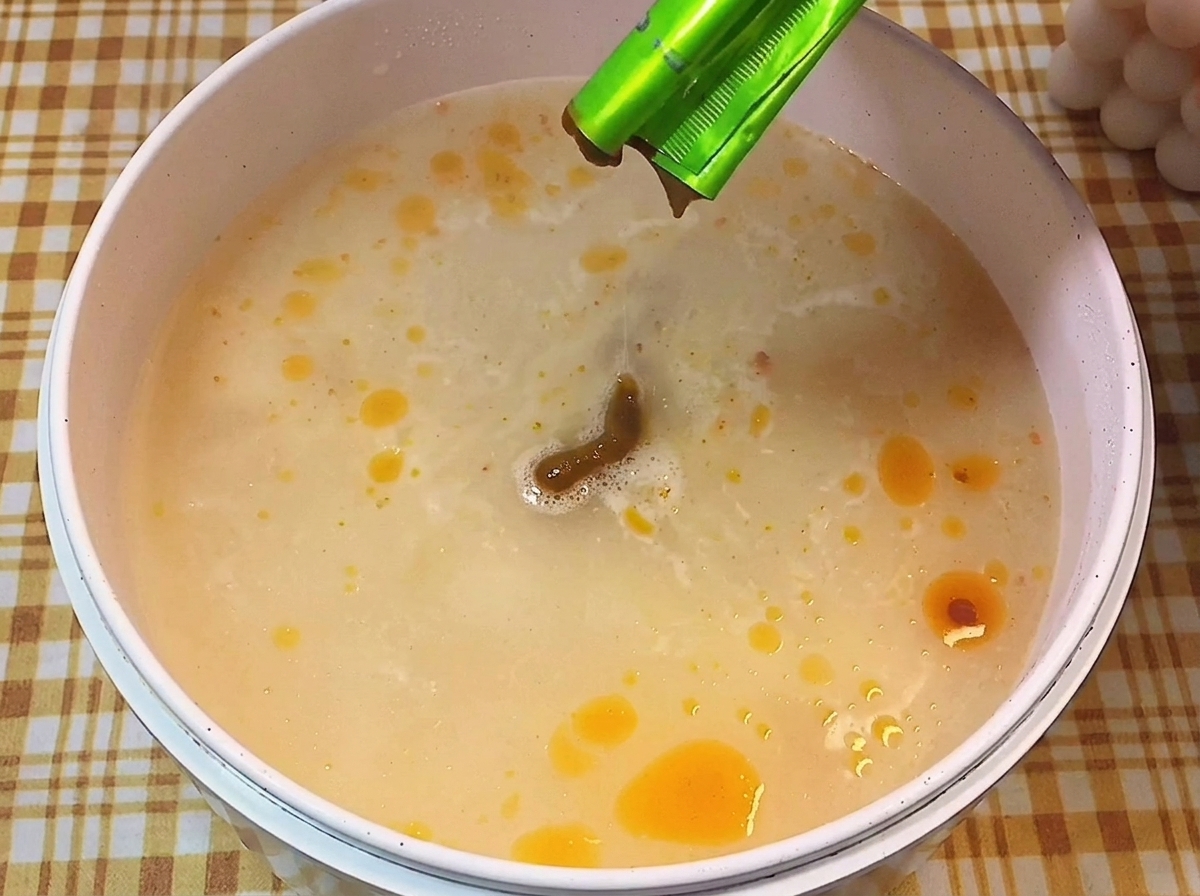 沸騰した鍋に、とんこつラーメンの液体スープを絞り入れている様子。
