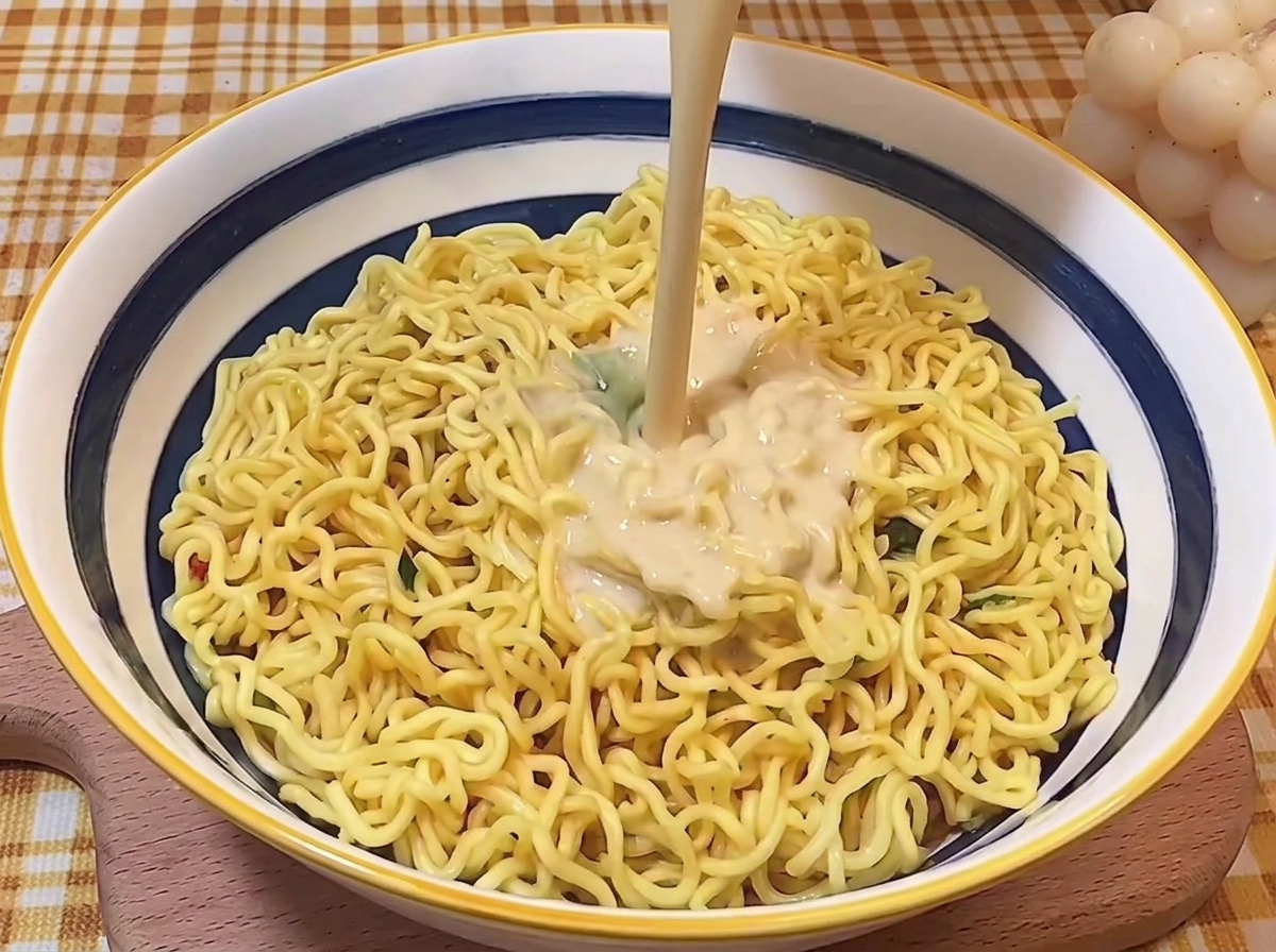 どんぶりに入れた麺の上から、熱々の濃厚とんこつスープを注いでいる様子。