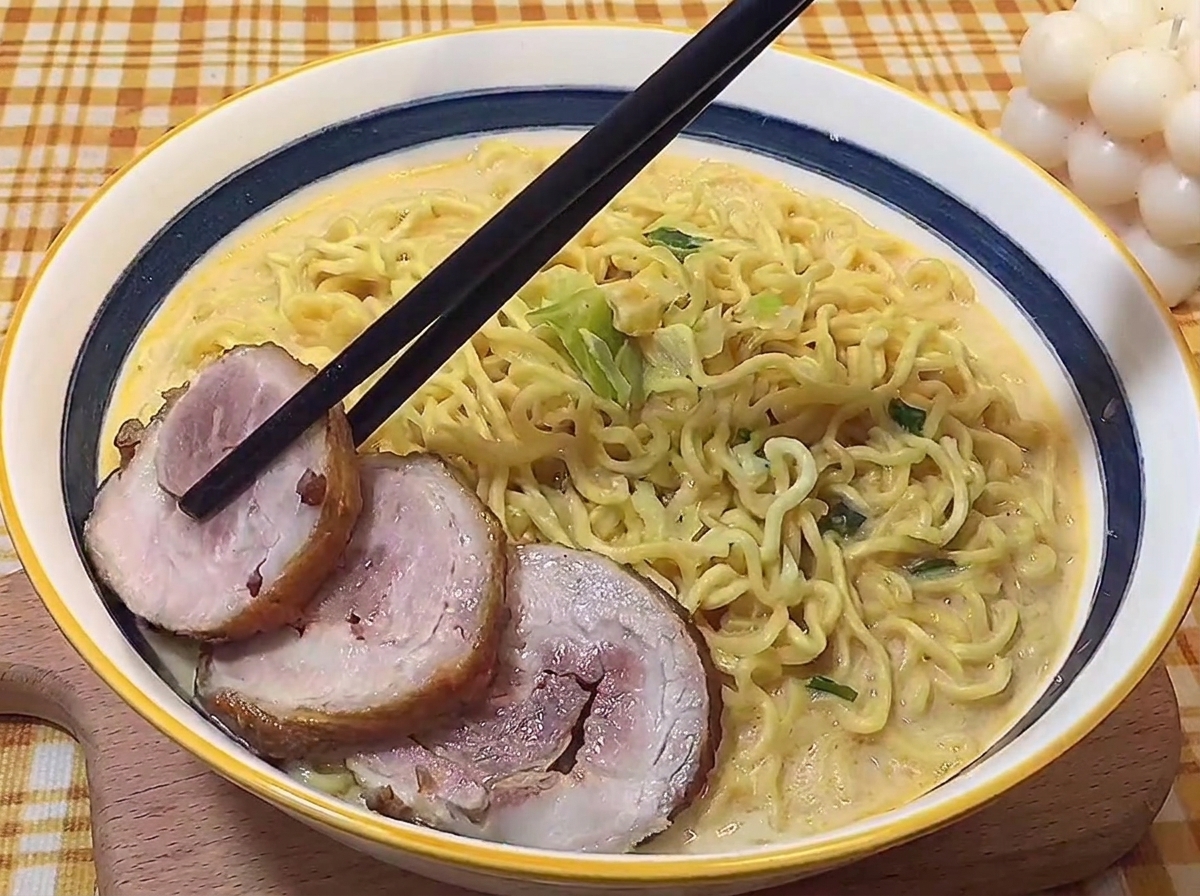 箸でスライスしたチャーシューをラーメンの上に丁寧に乗せている様子。