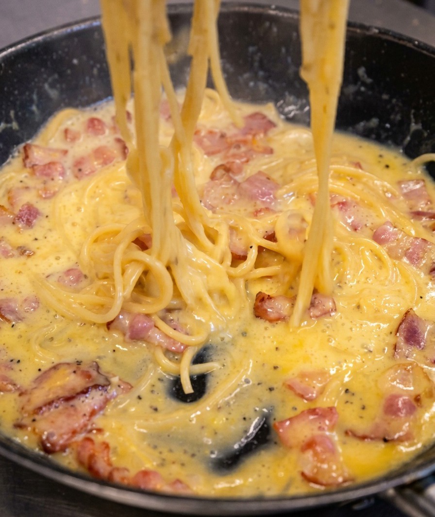 フライパンの中でパスタを煽り、ソースがとろりとクリーミーに変化していく様子。