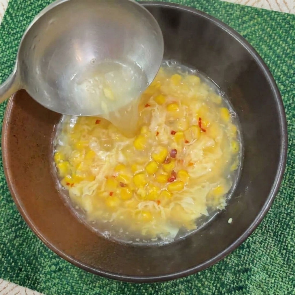 おたまを使って熱々の茹で汁をボウルに注ぐ様子