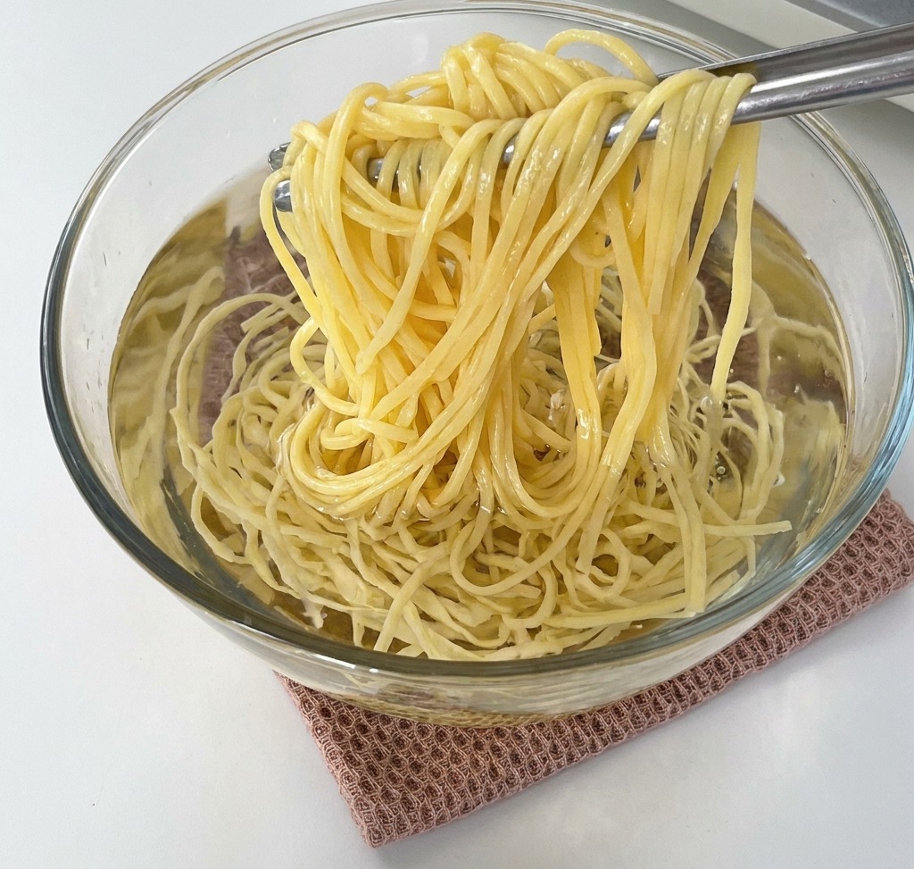 茹で上がったスパゲッティを冷水の入ったボウルに移している様子。