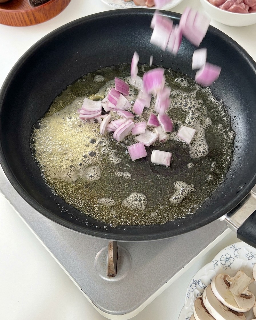 溶けたバターの中にみじん切りの赤玉ねぎを加えている様子。
