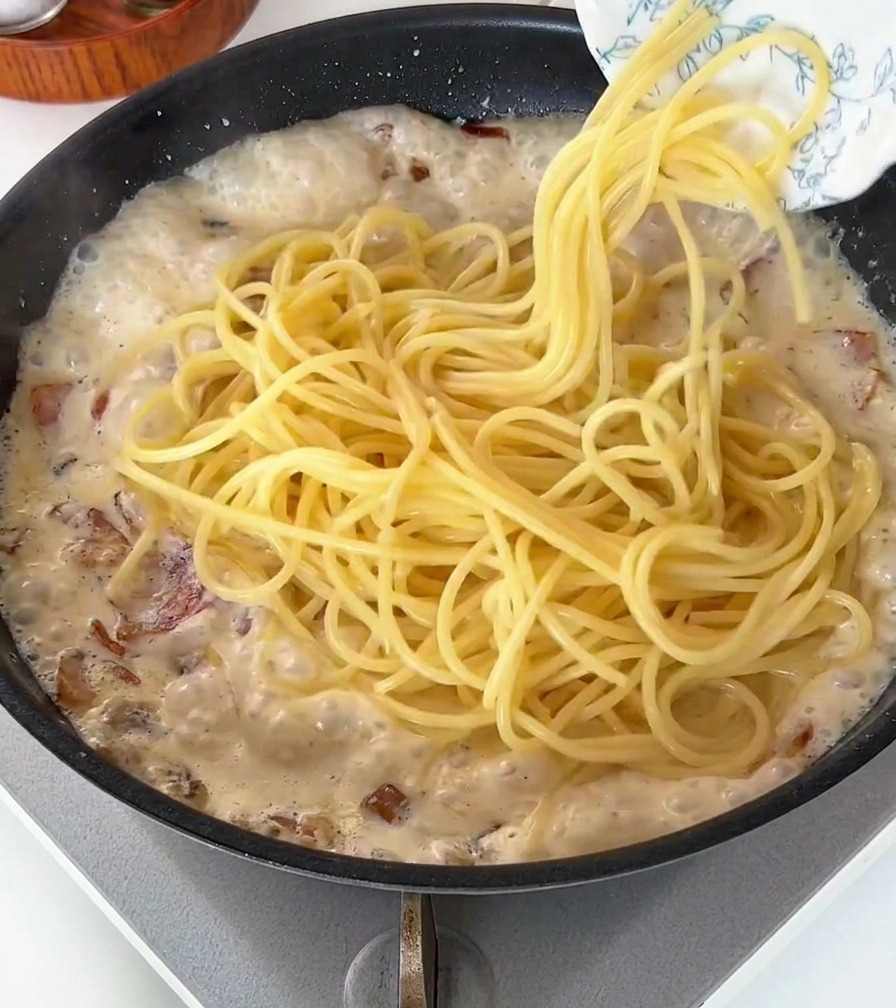クリームソースの中にスパゲッティを投入している様子。