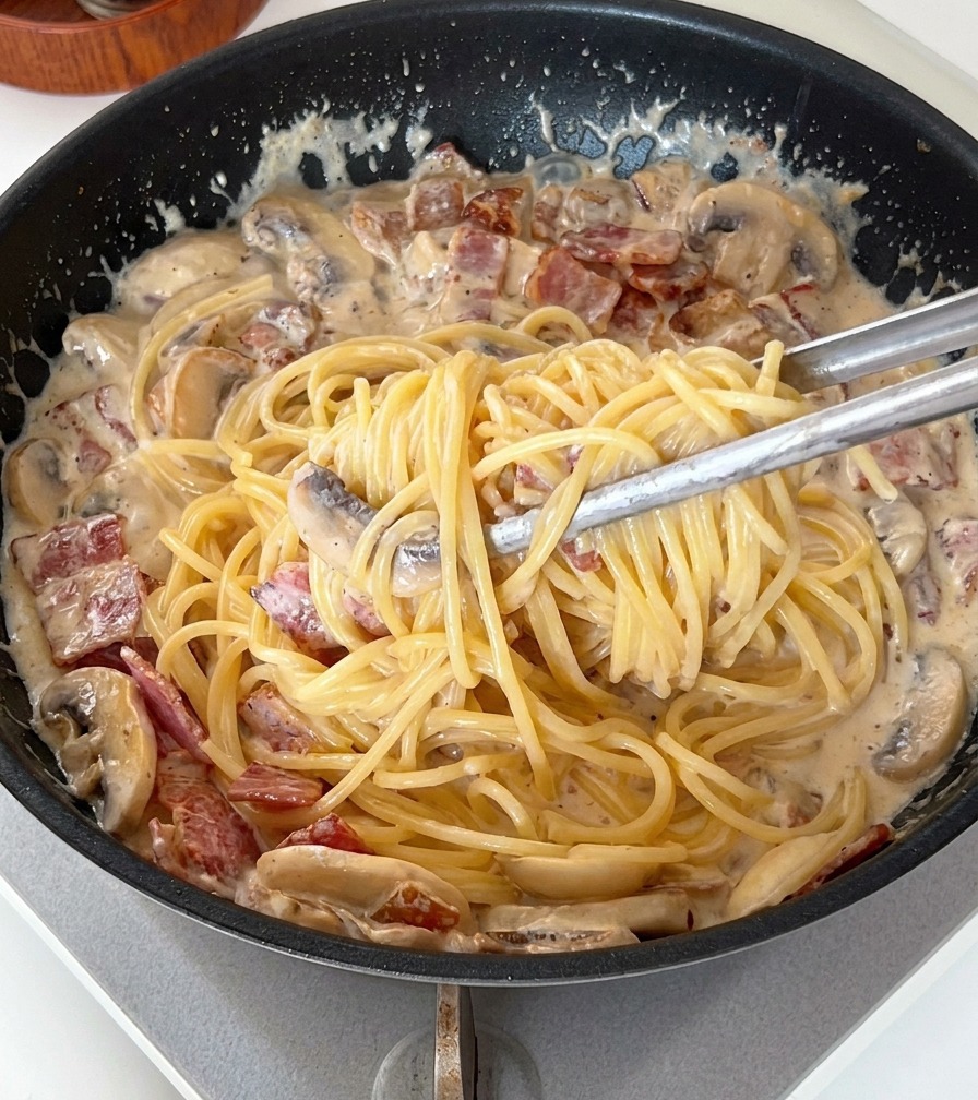 トングを使ってパスタと濃厚なクリームソースを絡めている様子。