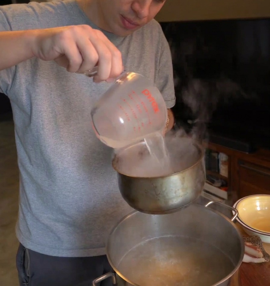 卵とチーズの混合物に、温かいパスタの茹で汁を少しずつ注いでいる様子。