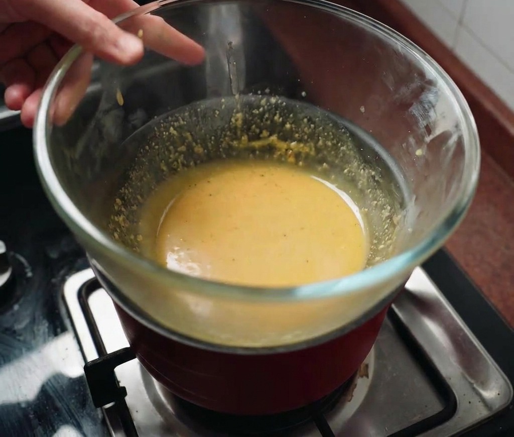 パスタを茹でている鍋の上にソースの入ったボウルを重ねて、蒸気で温めている様子。