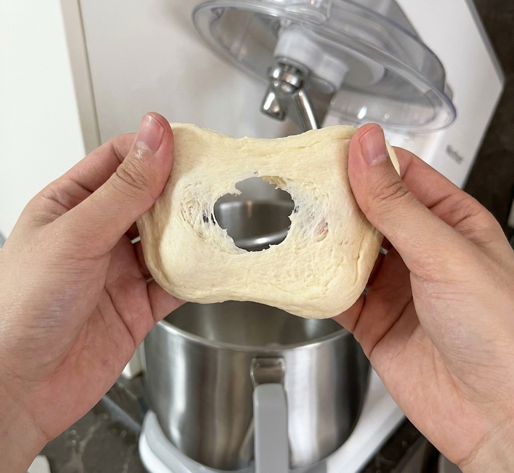 白っぽい生地を両手で広げ、薄い膜ができているか確認している様子