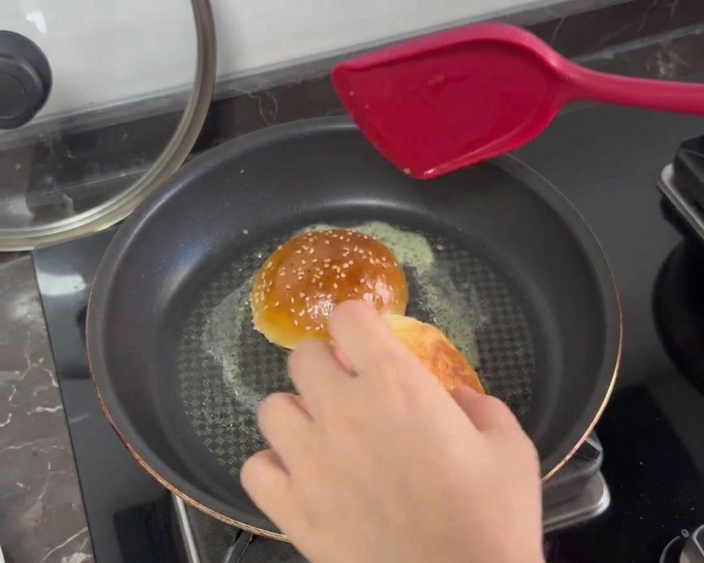 フライパンで溶けたバターと一緒に、半分に切ったバンズの断面を焼いている様子