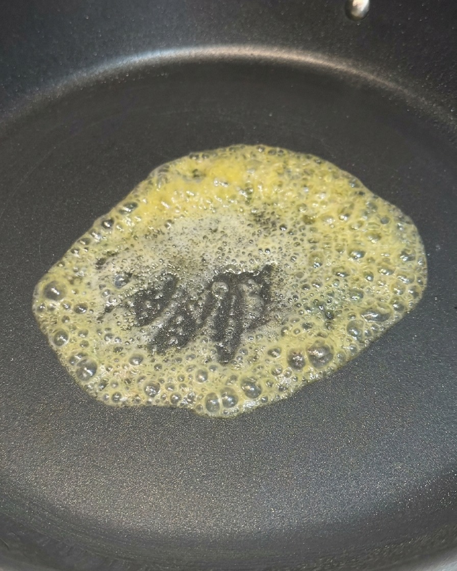 加熱したフライパンの中で、黄色いバターが溶けて泡立っている様子。