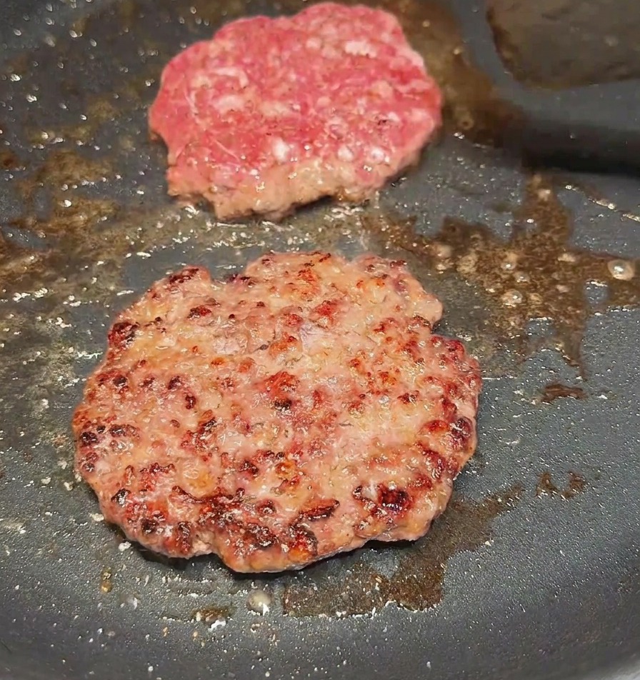 ヘラを使ってパティを裏返し、しっかりと焼き色のついた面が見えている様子。