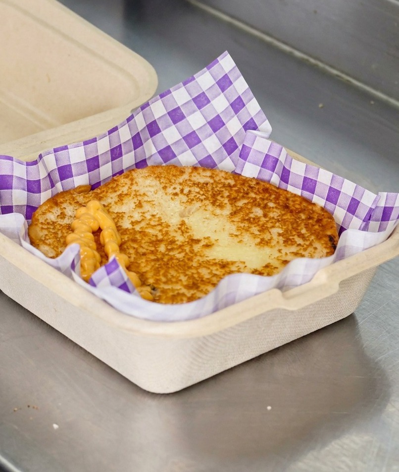 こんがり焼けたバンズの上に、オレンジ色のバーガーソースがジグザグにかけられている様子。