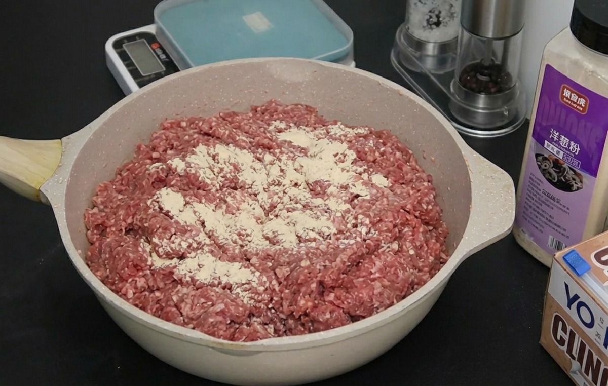 オニオンパウダーが振られた肉の上に、さらにガーリックパウダーを重ねて振りかけている様子。