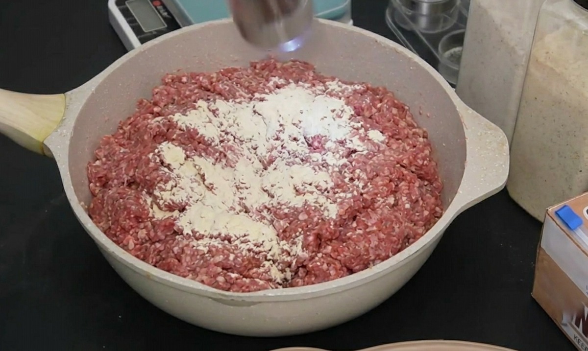 電動ミルを使って、味付けした肉の上に新鮮な黒胡椒を挽き入れているシーン。