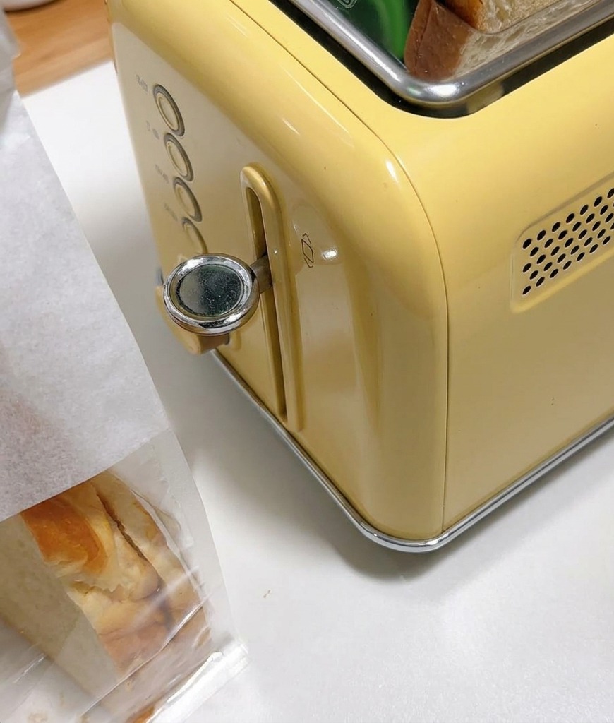 レトロな黄色いトースターのスロットに入った厚切り食パン。