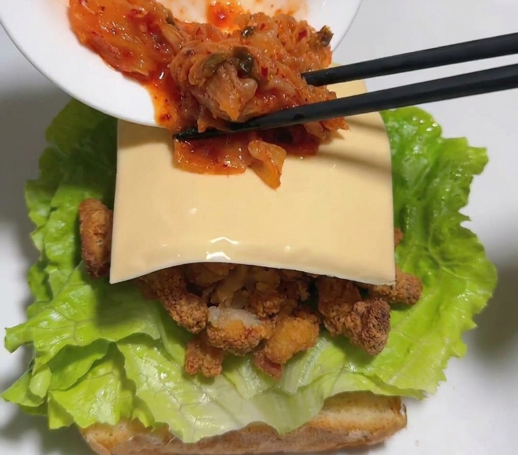 お箸でキムチをチーズの上に乗せる様子。