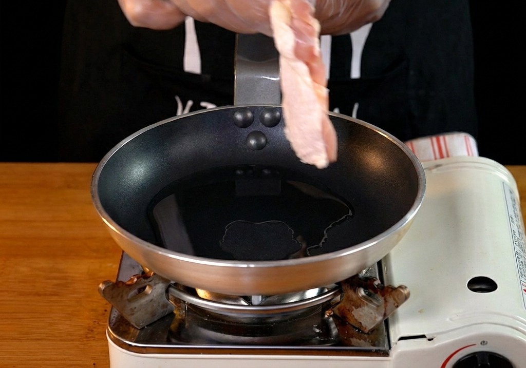 熱したフライパンに皮目を下にして鶏もも肉を入れる様子