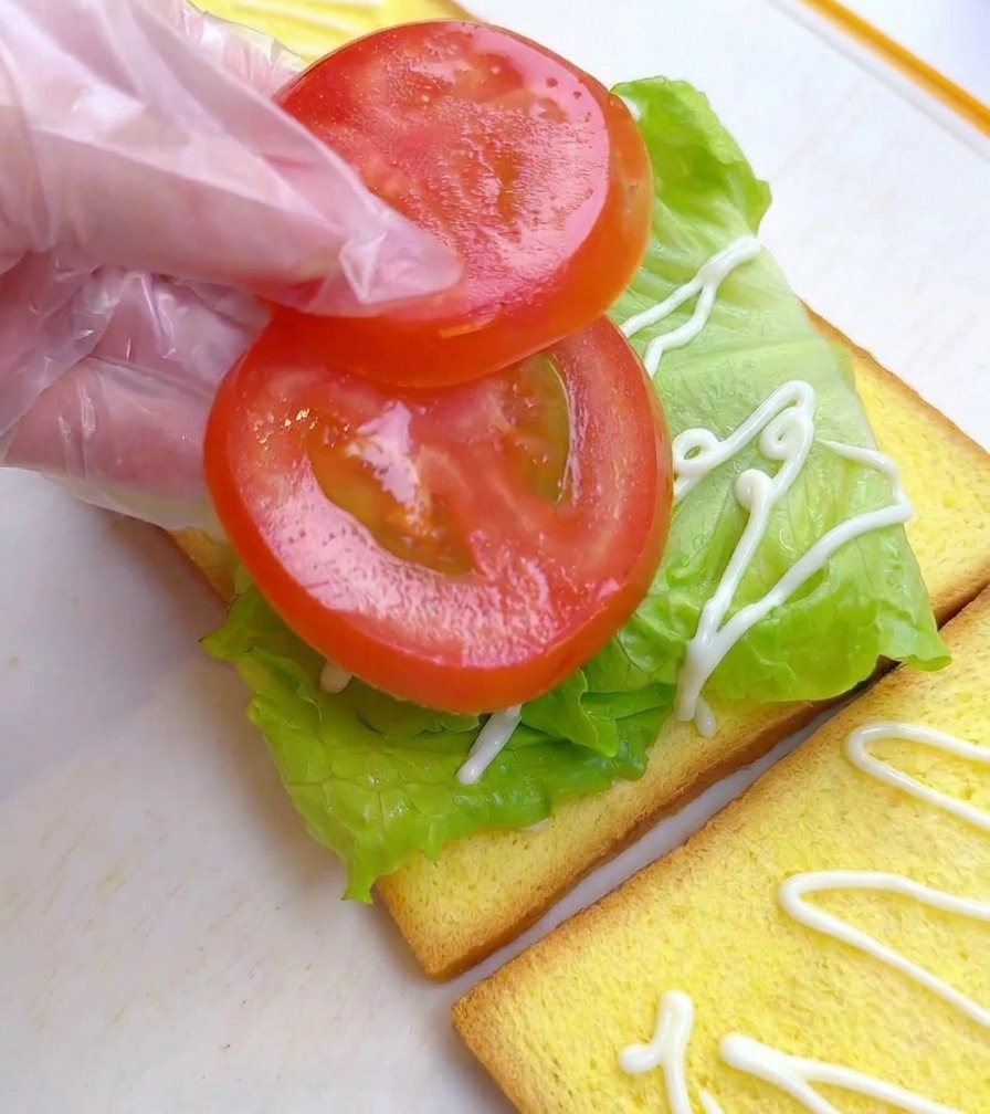 レタスの上に2枚の輪切りトマトを並べている様子。