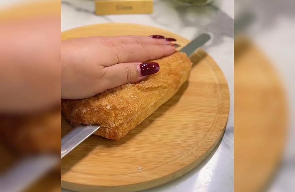 まな板の上で、パン切り包丁を使ってチャバタを横半分にカットしている様子。