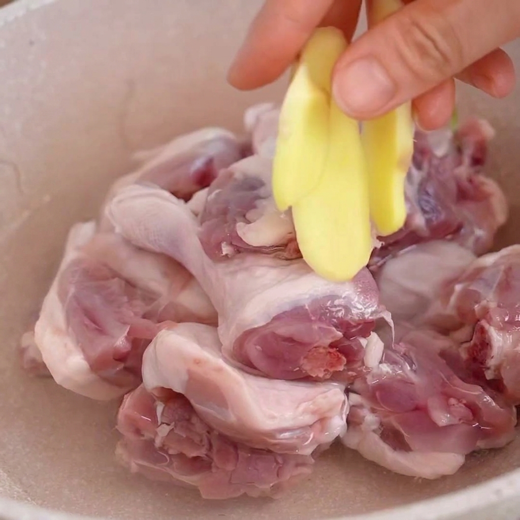 生姜スライスと一緒に鍋で下茹でされる鴨肉の様子。