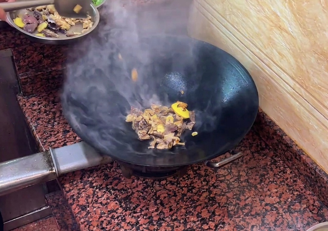薬味とともに鍋で炒められる、鴨レバー腸詰めのスライス。