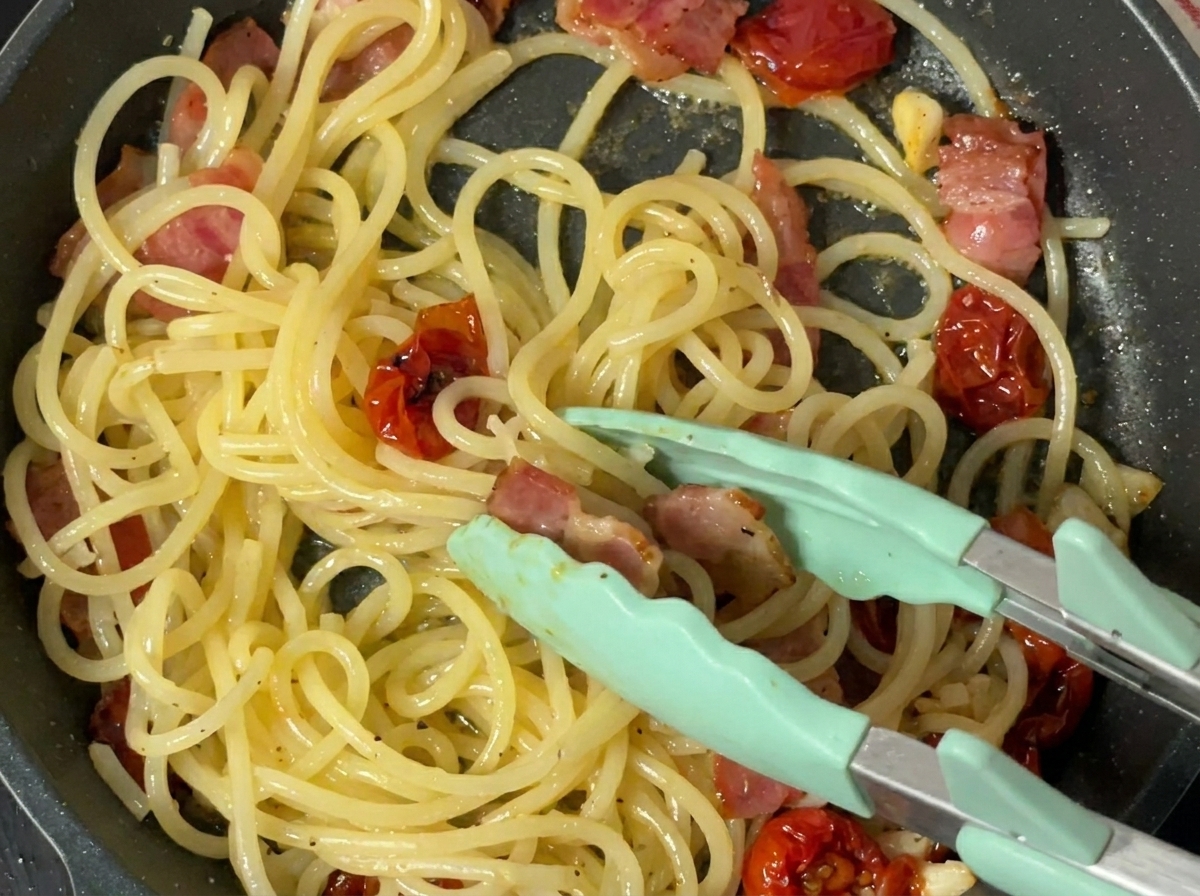 フライパンの中のパスタに黒胡椒を挽きかけている様子。
