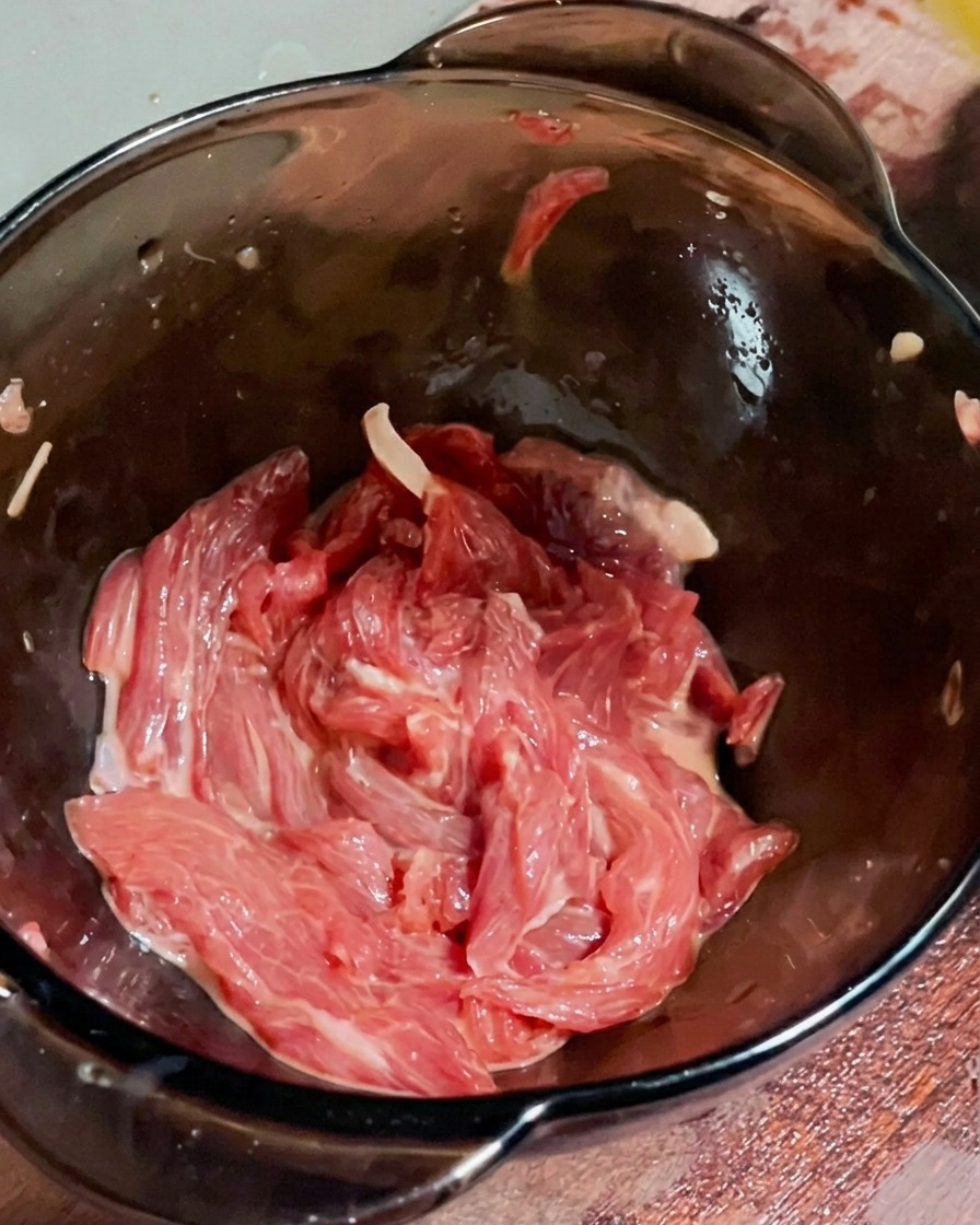 下味をつけた牛肉にサラダ油をまわしかけている様子。