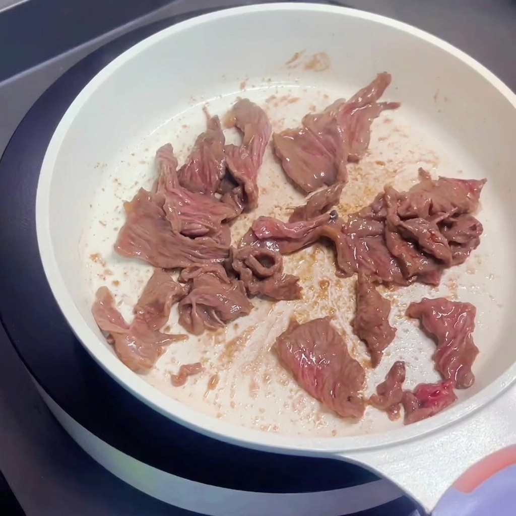 フライパンで牛肉を中強火で炒め、表面に焼き色が付いている様子。