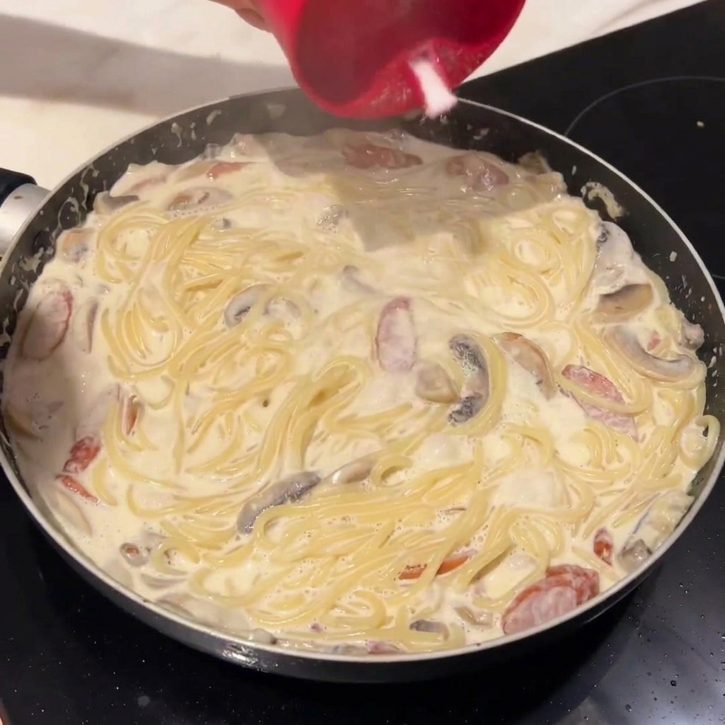 パスタをクリームソースに絡めている様子。
