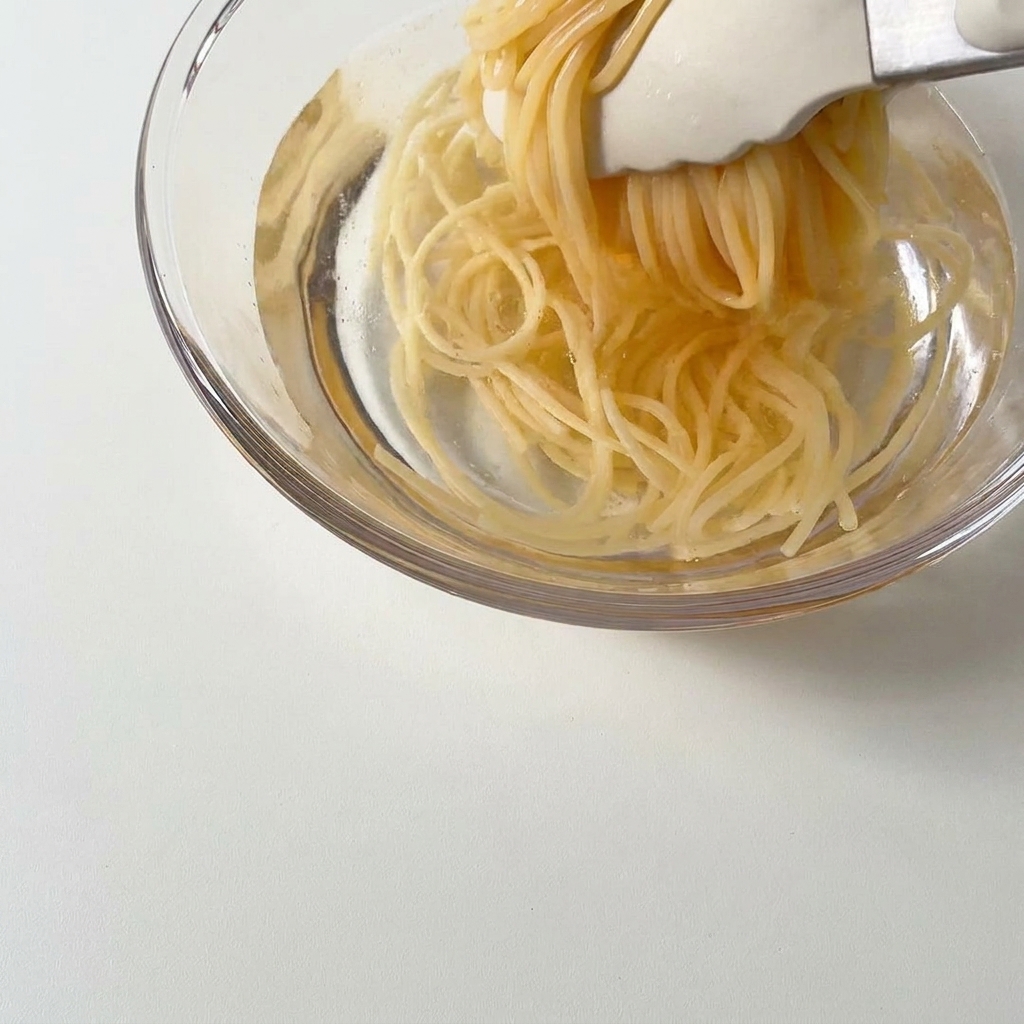 茹で上がったスパゲッティを冷水に移す様子。