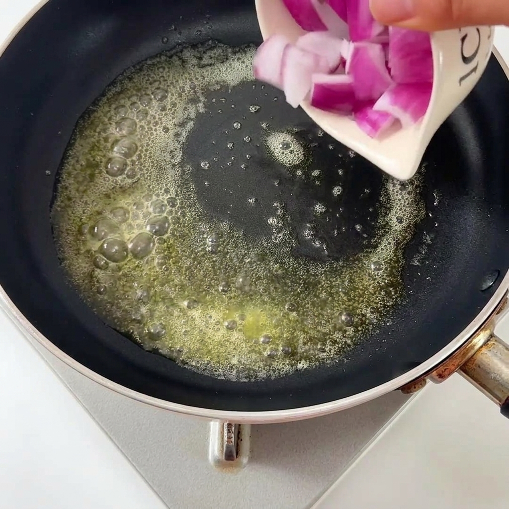 バターの入ったフライパンで炒められる玉ねぎ。