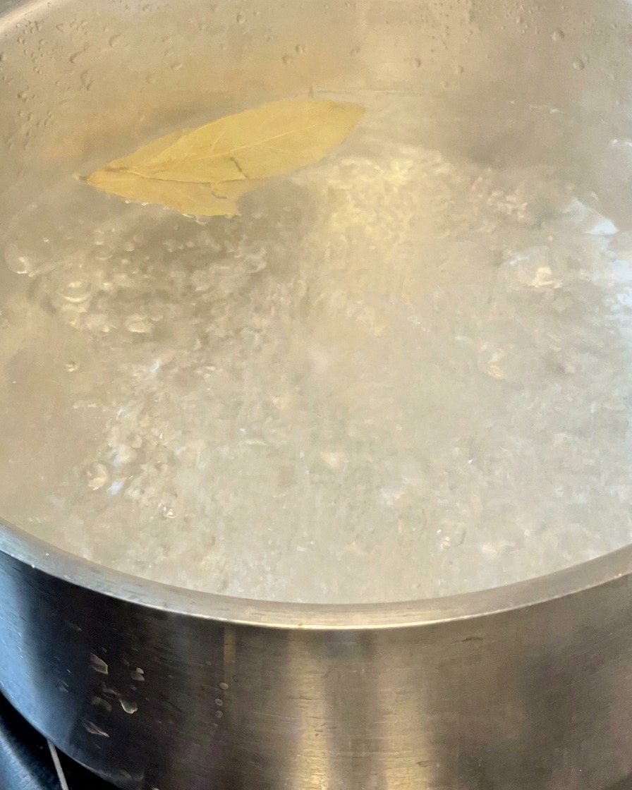 鍋で茹でられているパスタと、浮かぶ2枚のローリエ。