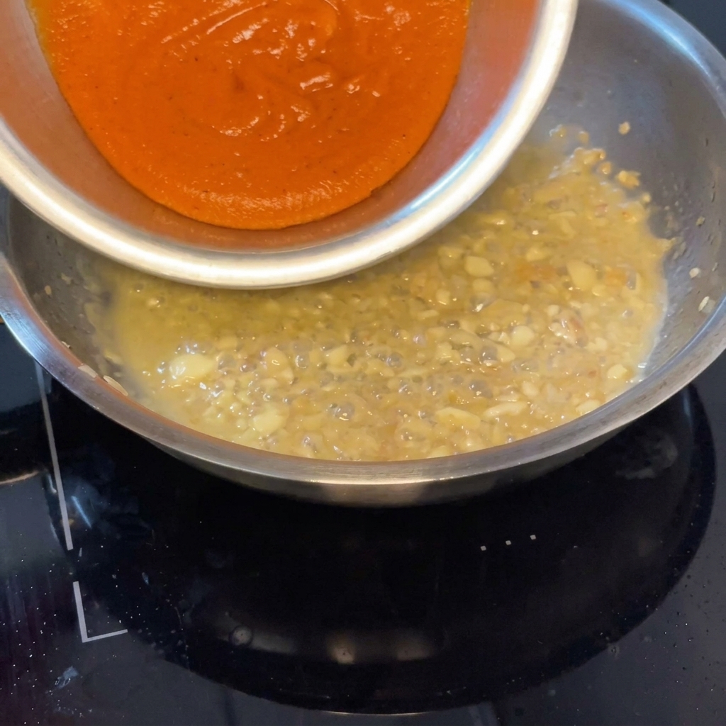 あさりの旨味が出たソースに、焼きパプリカソースを加えて混ぜ合わせる様子。