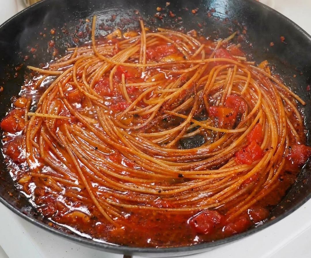 フライパンの中で、濃厚なトマトソースが絡んだパスタのアップ。