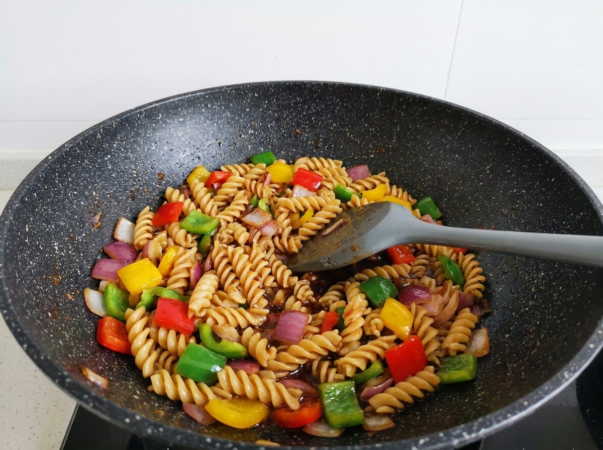 ヘラを使って全体を混ぜ合わせ、ソースがしっかりと絡んだパスタ炒め。