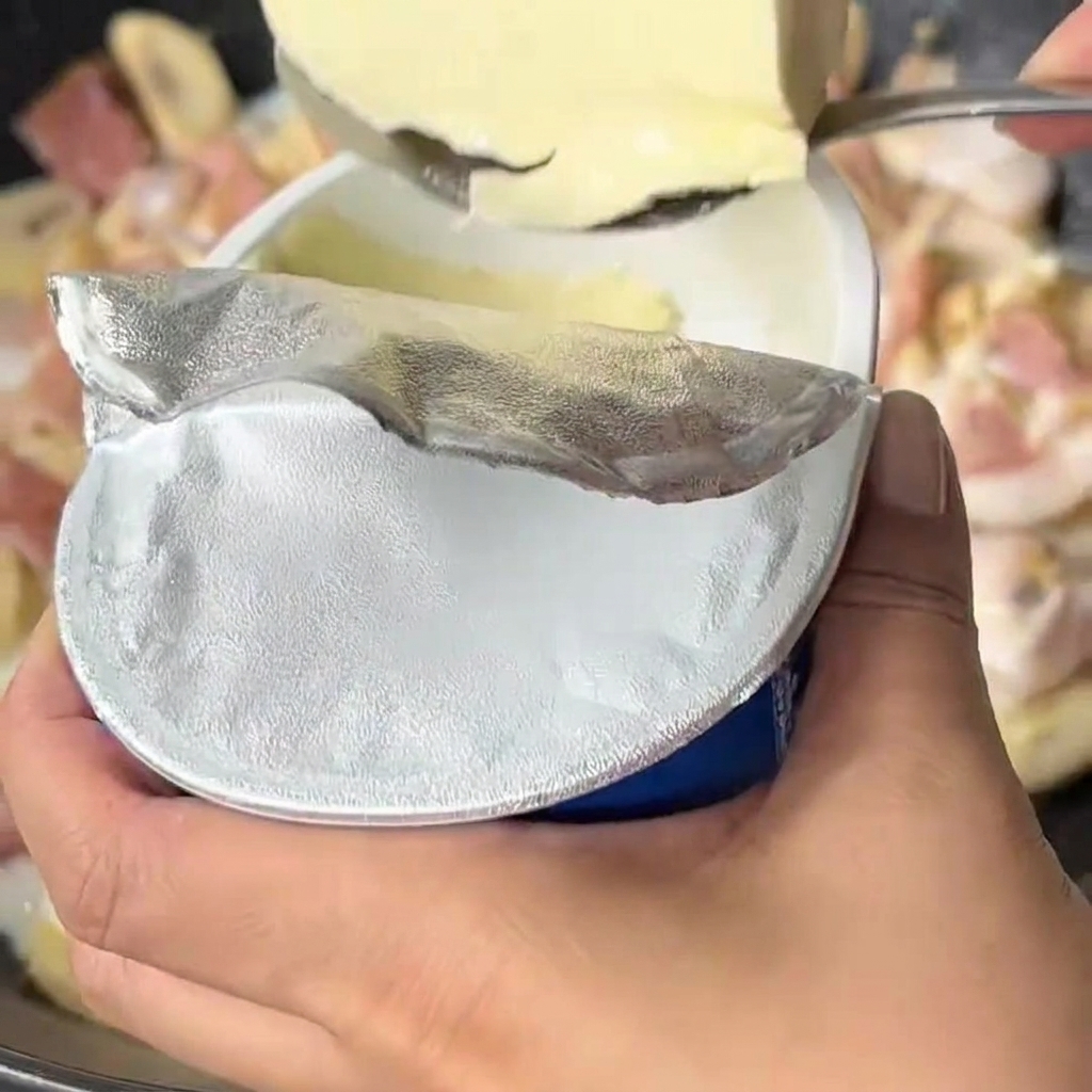 ふつふつと煮立つ牛乳と野菜のソースに、クリームチーズを加えている様子。