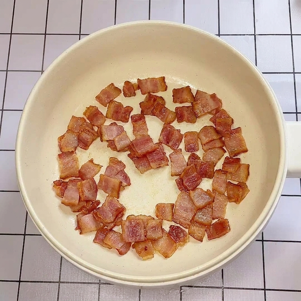 フライパンでベーコンがカリカリに炒められている様子。