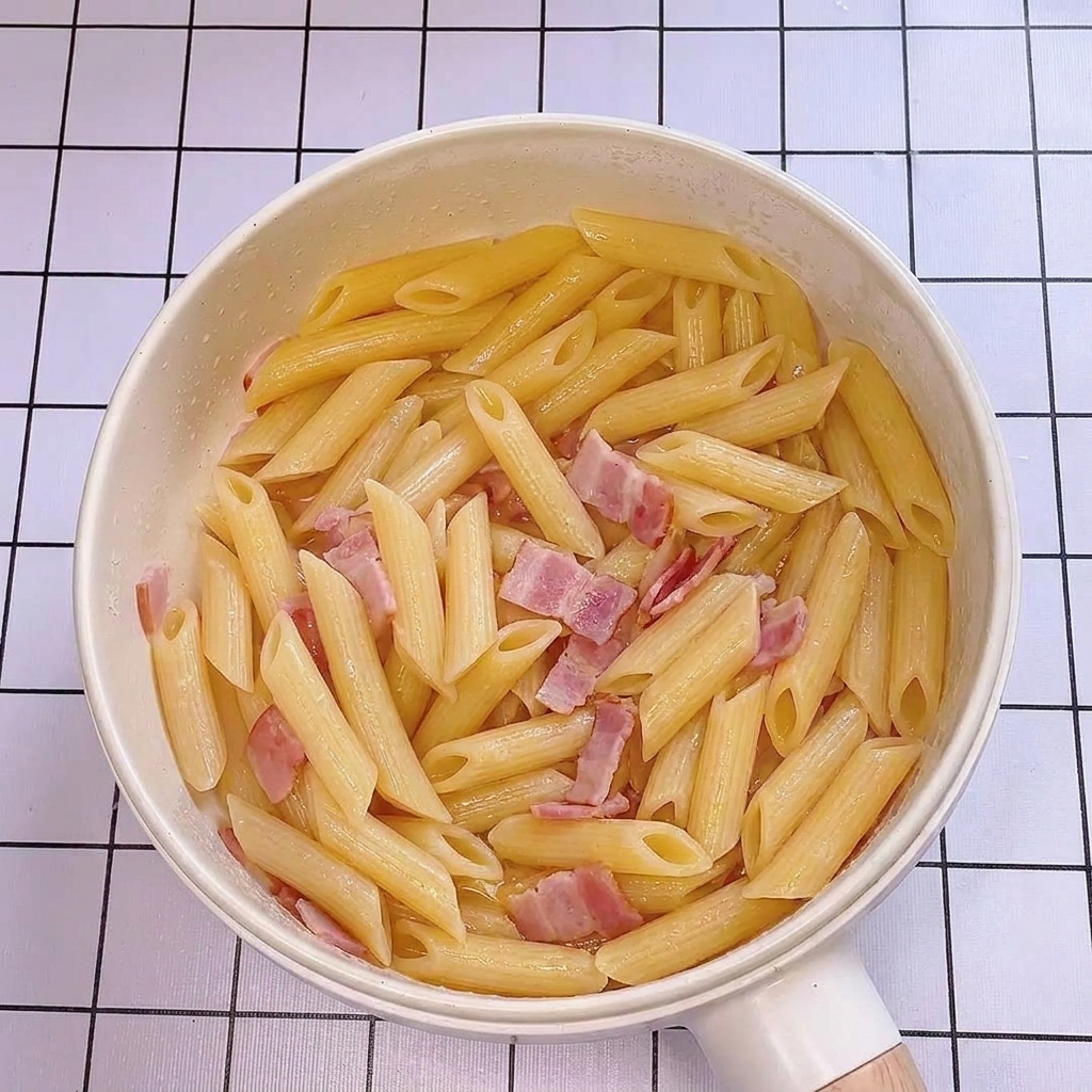 フライパンにパスタの茹で汁を加え、艶が出ている様子。