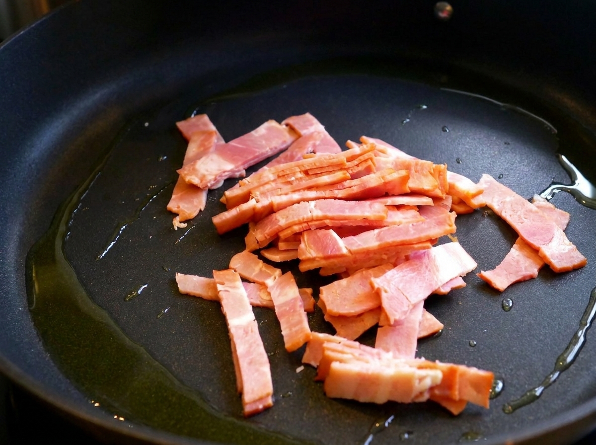 フライパンでオリーブオイルを引いたベーコンがカリカリに焼けている様子。