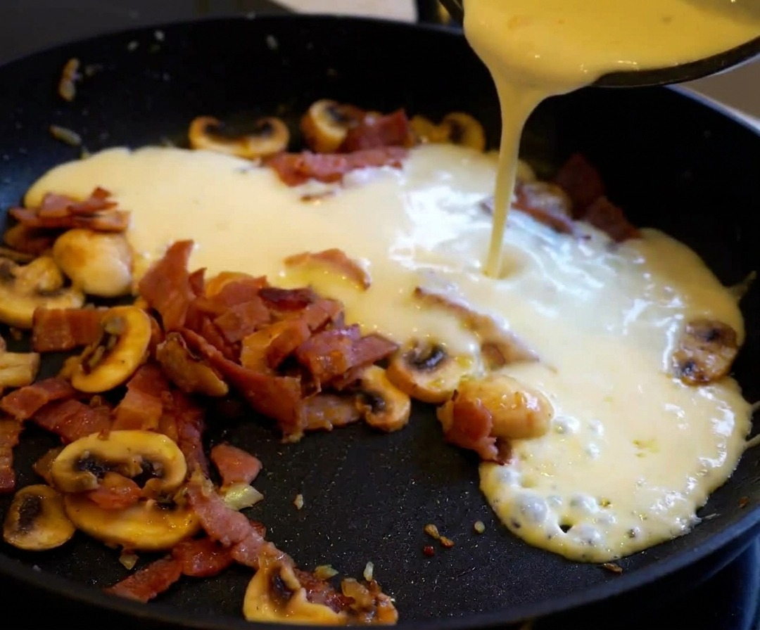 茹で上がったパスタをソースの入ったフライパンに加え、絡めている様子。