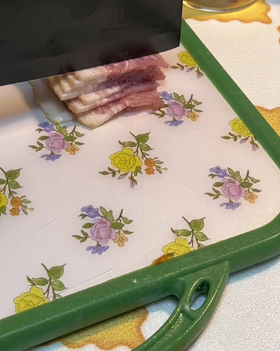 まな板の上でベーコンを細かく切っている様子。