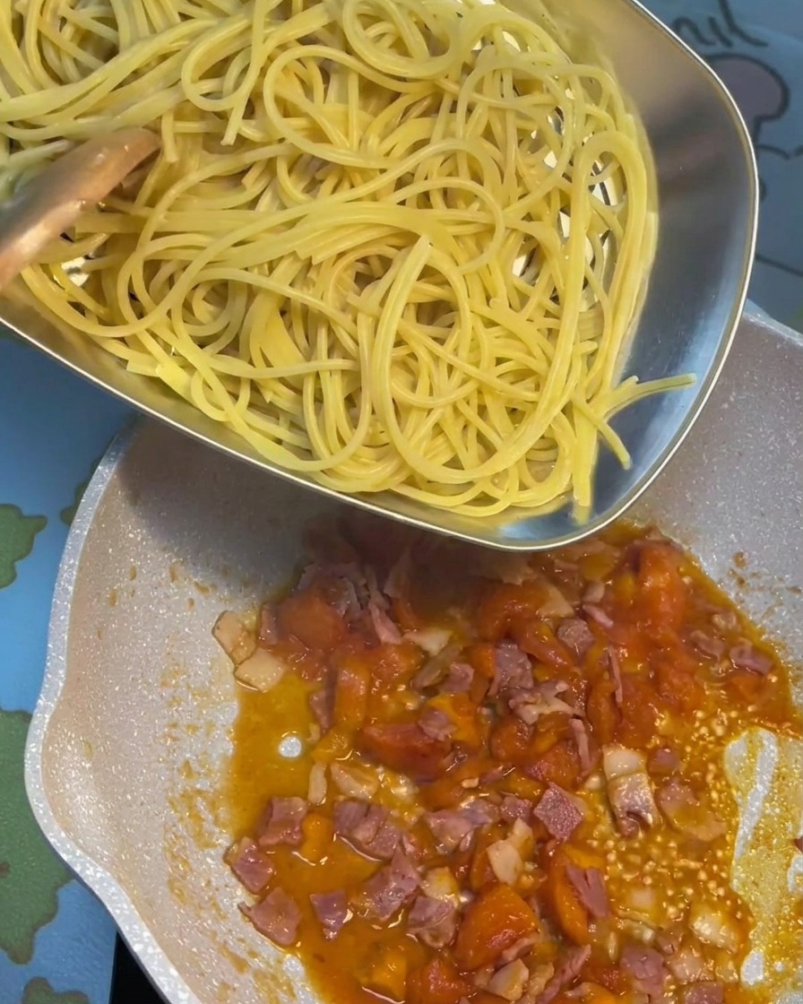 茹で上がったパスタをソースの入ったフライパンに移している様子。