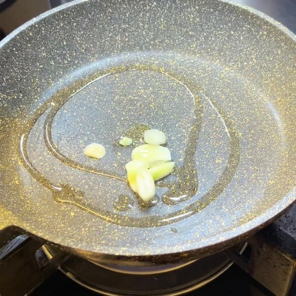 フライパンのオリーブオイルでにんにくを炒める様子