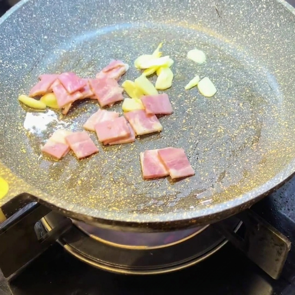 フライパンでにんにくとベーコンを炒める様子